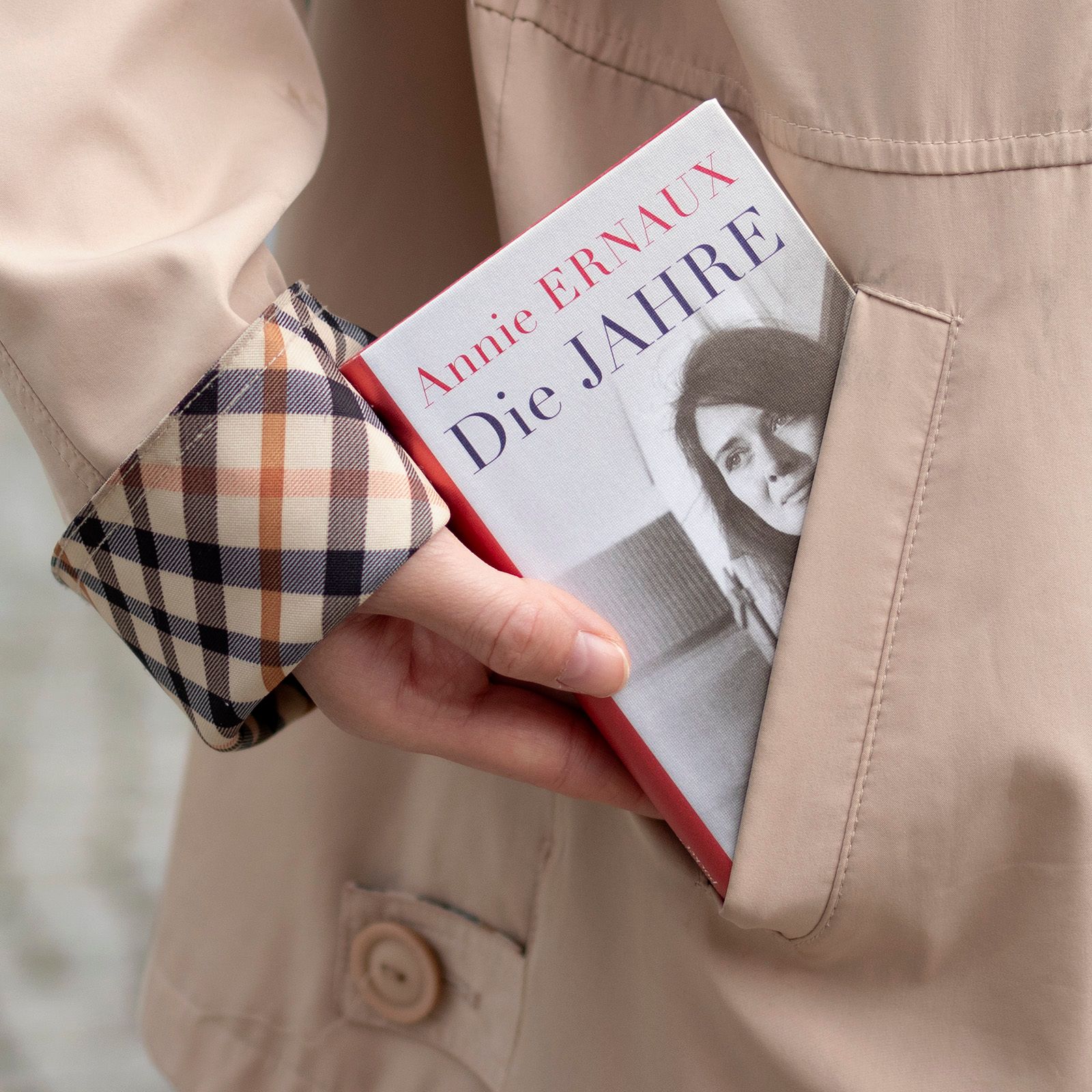 Foto einer Manteltasche, aus der das Buch "Die Jahre" von Annie Ernaux herausschaut, in der Ausgabe der Reihe Suhrkamp Pocket