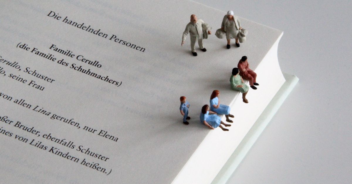 Aufgeschlagener Ausschnitt des Buches »Meine Geniale Freundin«, auf dem sieben Miniaturfiguren sitzen und stehen.
