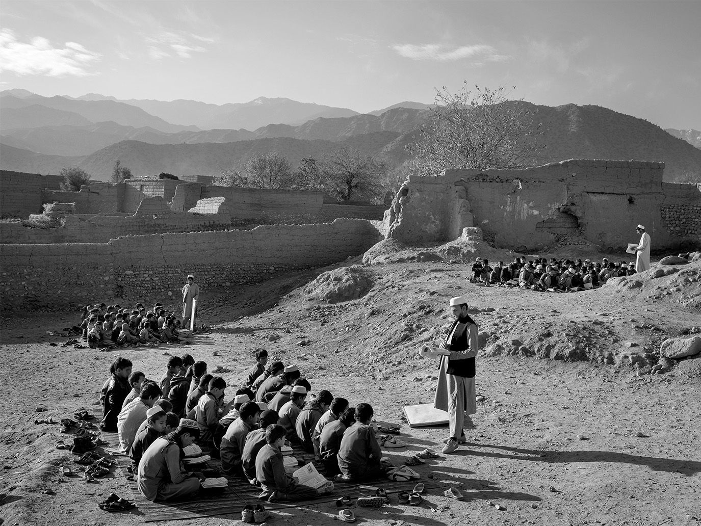 Afghanische Gebetsschüler, draußen auf dem Boden sitzend, vor ihnen steht ein Lehrer. © Kaveh Rostamkhani