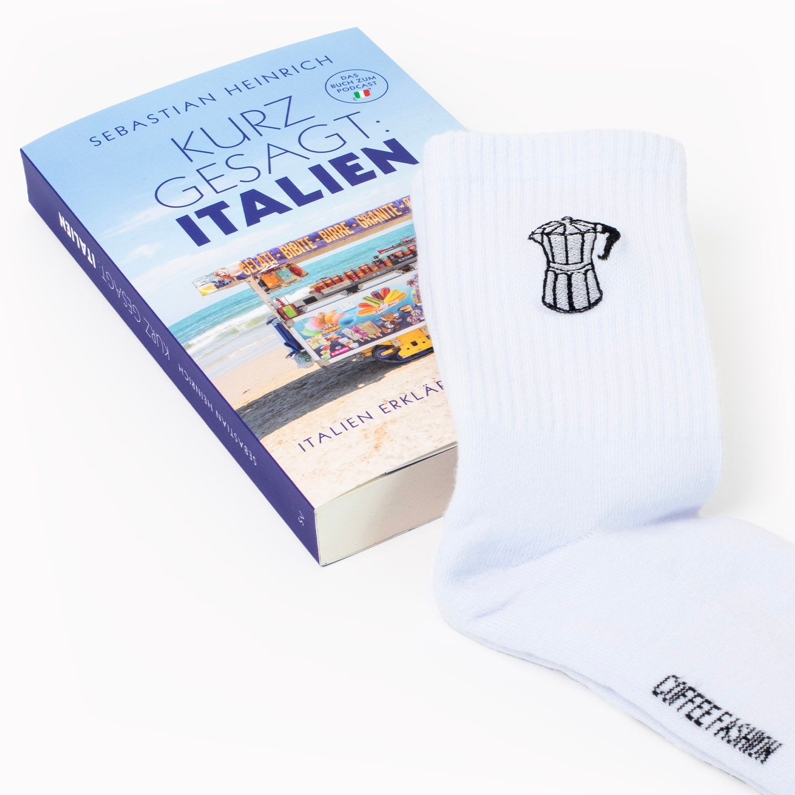 Das Buch »Kurz gesagt: Italien« mit Socken, auf die eine Bialetti-Kanne bestickt ist. 