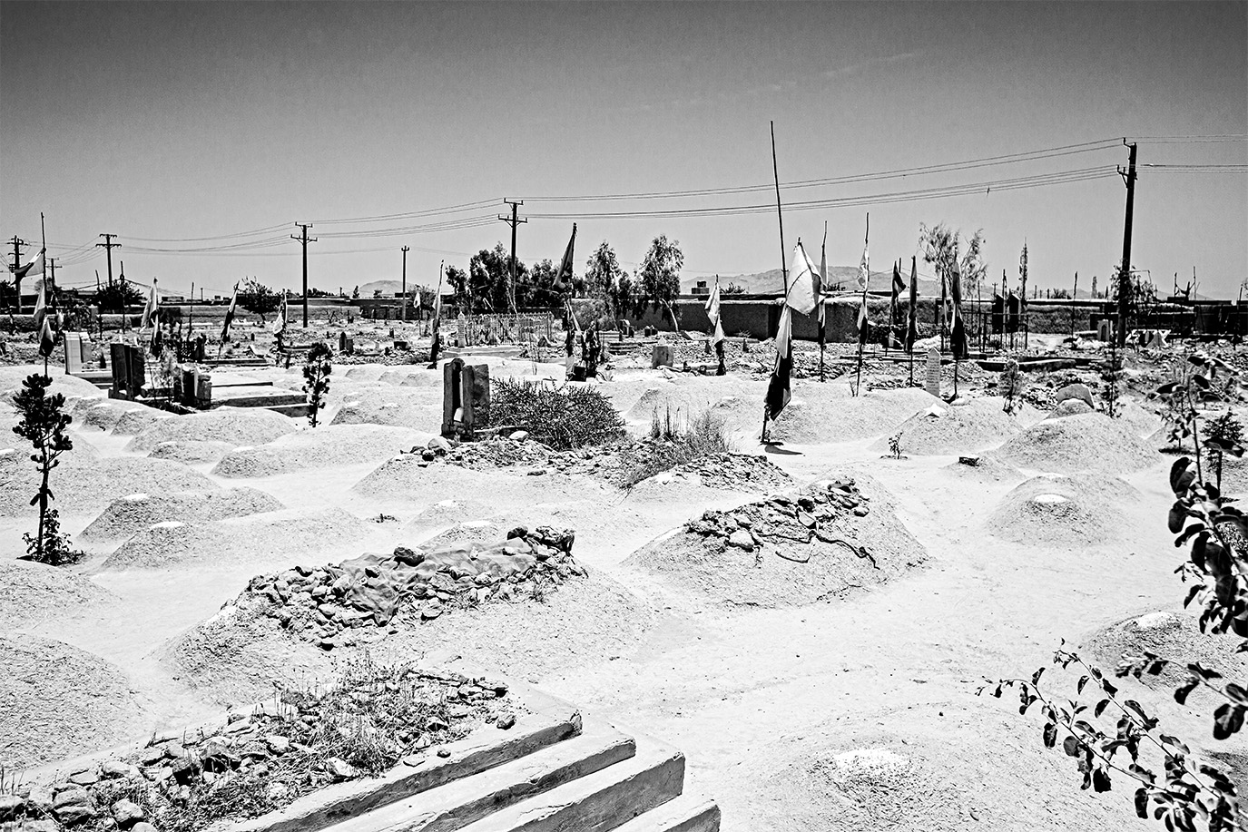 Eine schwarz-weiß Fotografie eines afghanischen Friedhofs, bestehend aus Sandhügeln. © Andy Spyra